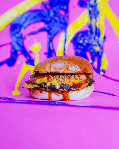 Burger su sfondo rosa con schizzi di vernice