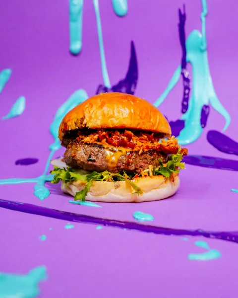 Burger su sfondo viola con schizzi di vernice
