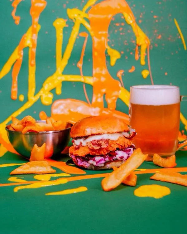 Burger, patatine e birra su uno sfondo colorato